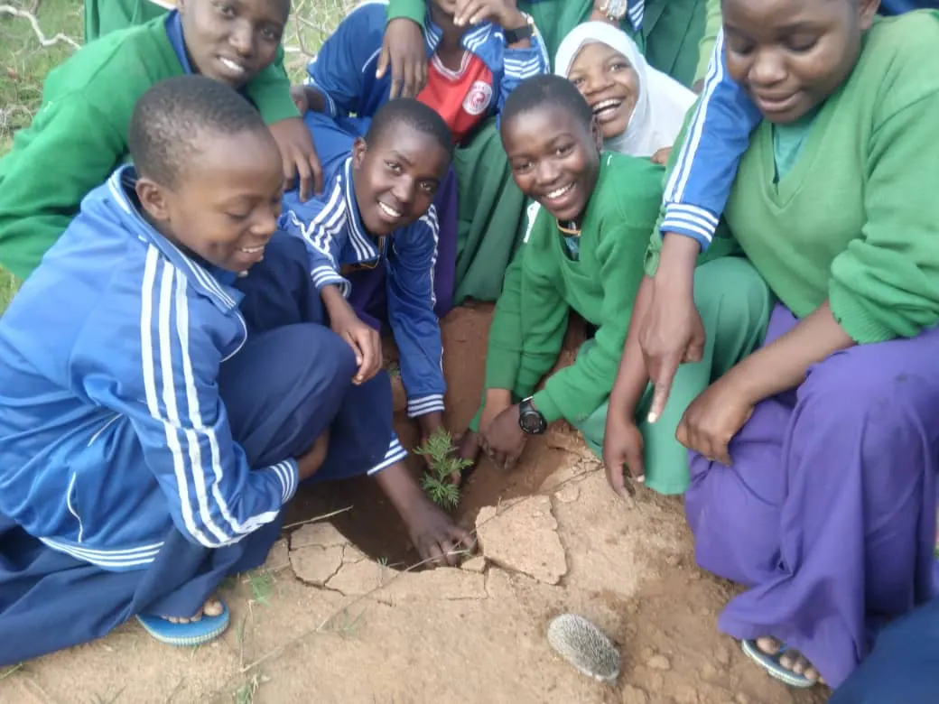 School pupils planting a seedling with a Save the Planet facilitator